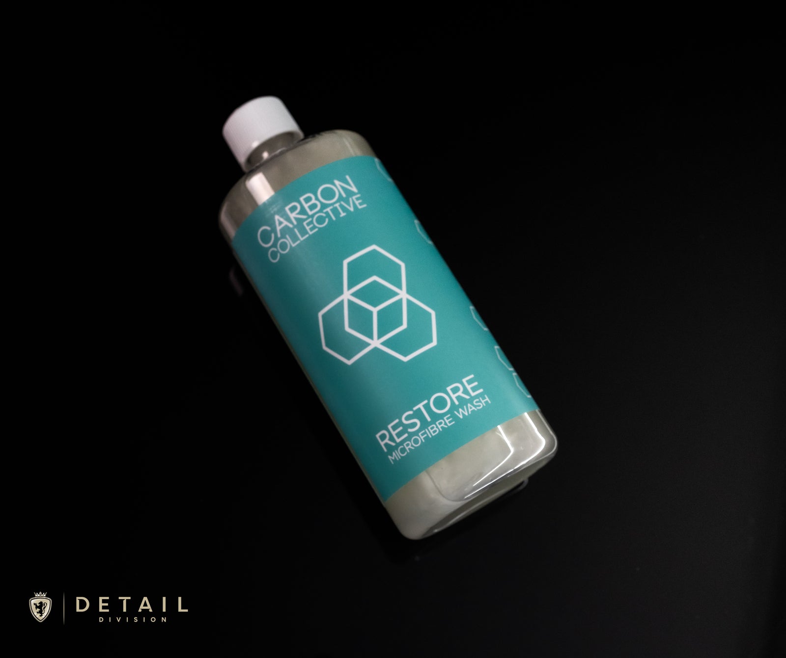 A bottle of Carbon Collective Restore Microfibre Wash on a dark background with the brand's logo visible on the label.